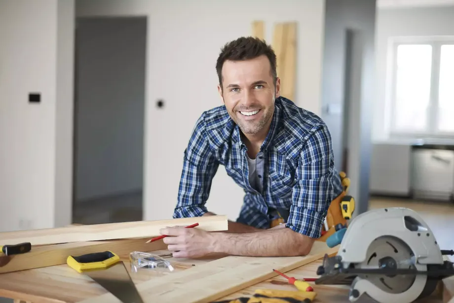 glücklicher Arbeiter fotografiert während seiner Arbeiten in einem Haus
