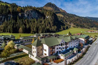 Steildächer in grüner Farbe im Robinson Club Amadé 1 mit weißer Fassade und Balkonen für eine schöne Aussicht auf Land und Berge