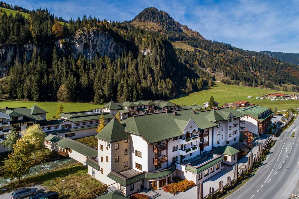 Steildächer in grüner Farbe im Robinson Club Amadé 1 mit weißer Fassade und Balkonen für eine schöne Aussicht auf Land und Berge
