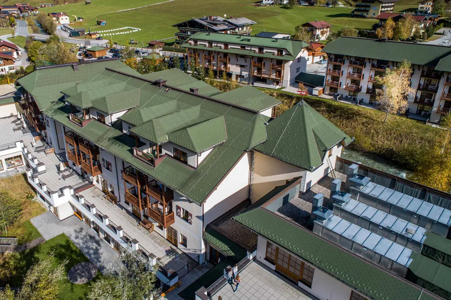 Hotel Robinson Club Amadé mit grünem Steildach und weißer Fassade mit Balkon und schönen Ausblick 