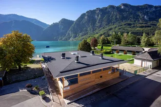 modernes Strandbad am Attersee mit Holzfassade und grauen Dach, Haus mit See- und Bergblick