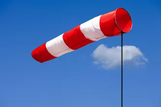 Windfahne weht im Wind und im Hintergrund sieht man den fast klaren, blauen Himmel